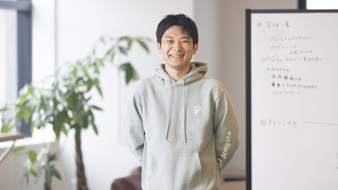 ホワイトボードのあるオフィスで灰色のパーカを着た男性