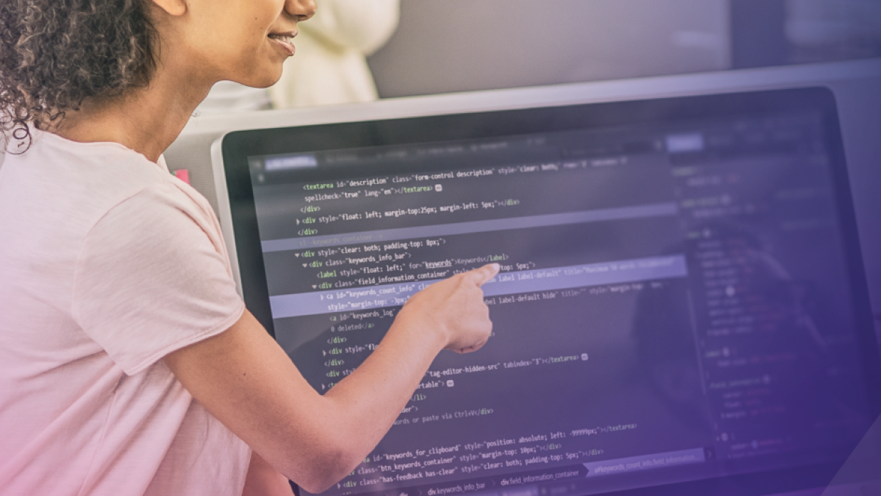 l'immagine mostra una donna che indica uno schermo di pc che mostra linguaggio di programmazione