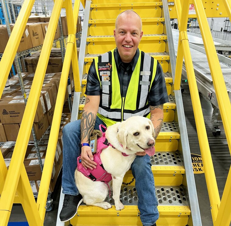 Aspen, a service dog, poses with her owner, an Amazon employee.