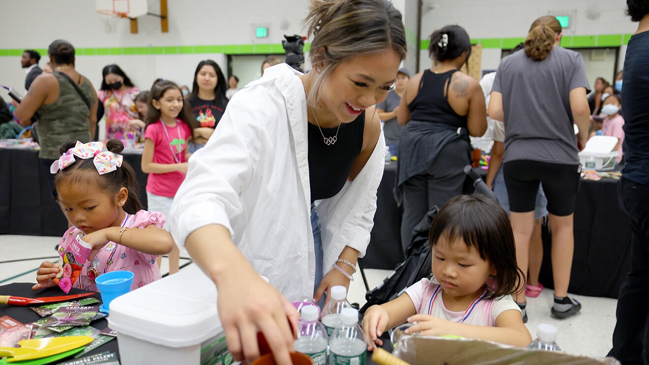 Suni Lee站在两个小女孩中间,她们都在学校玩STEAM活动。