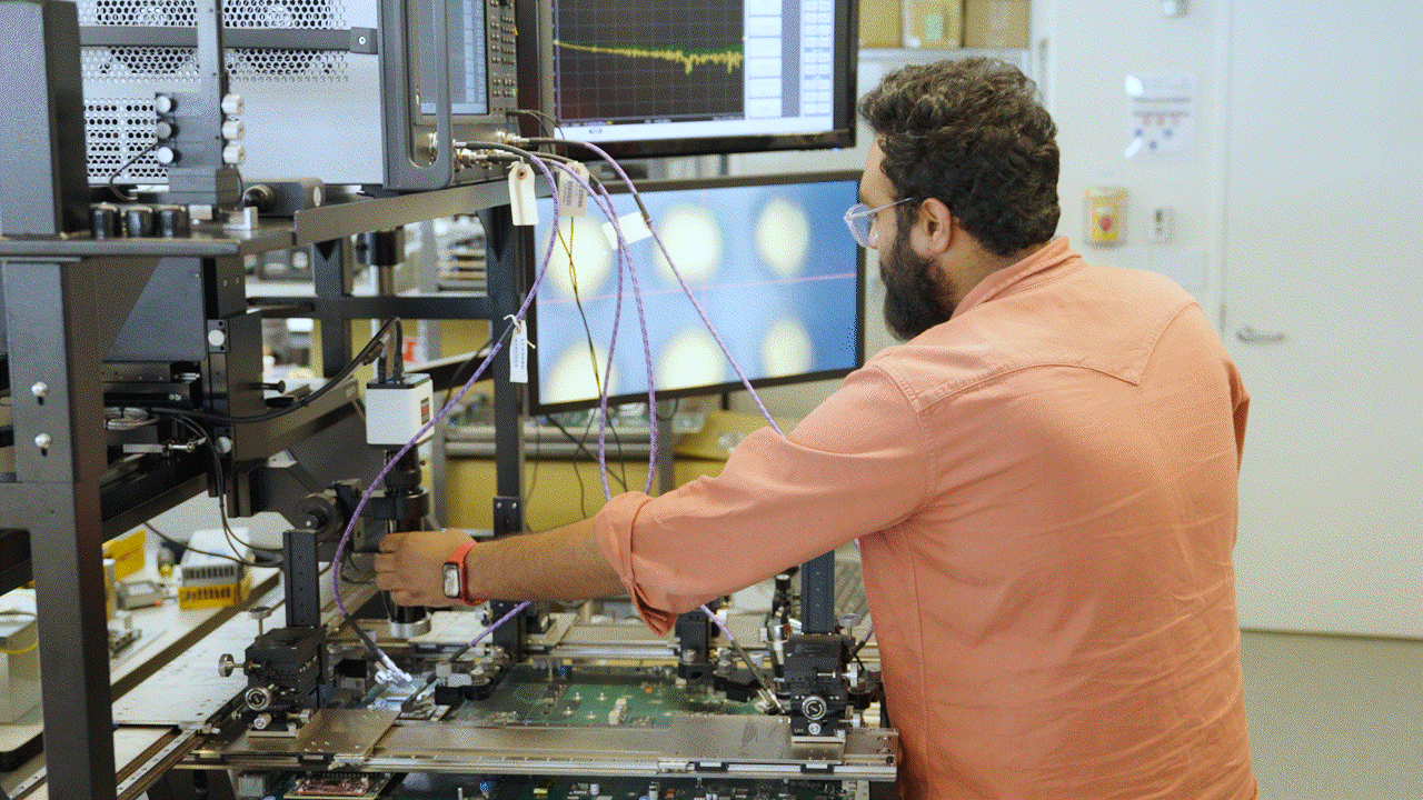 An engineer in an AWS lab examines data visualizations, zooming in and out of elements on a large monitor display