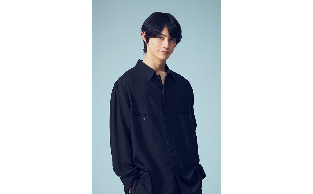 男性の上半身ポートレート。両手をポケットに入れて立っている。
