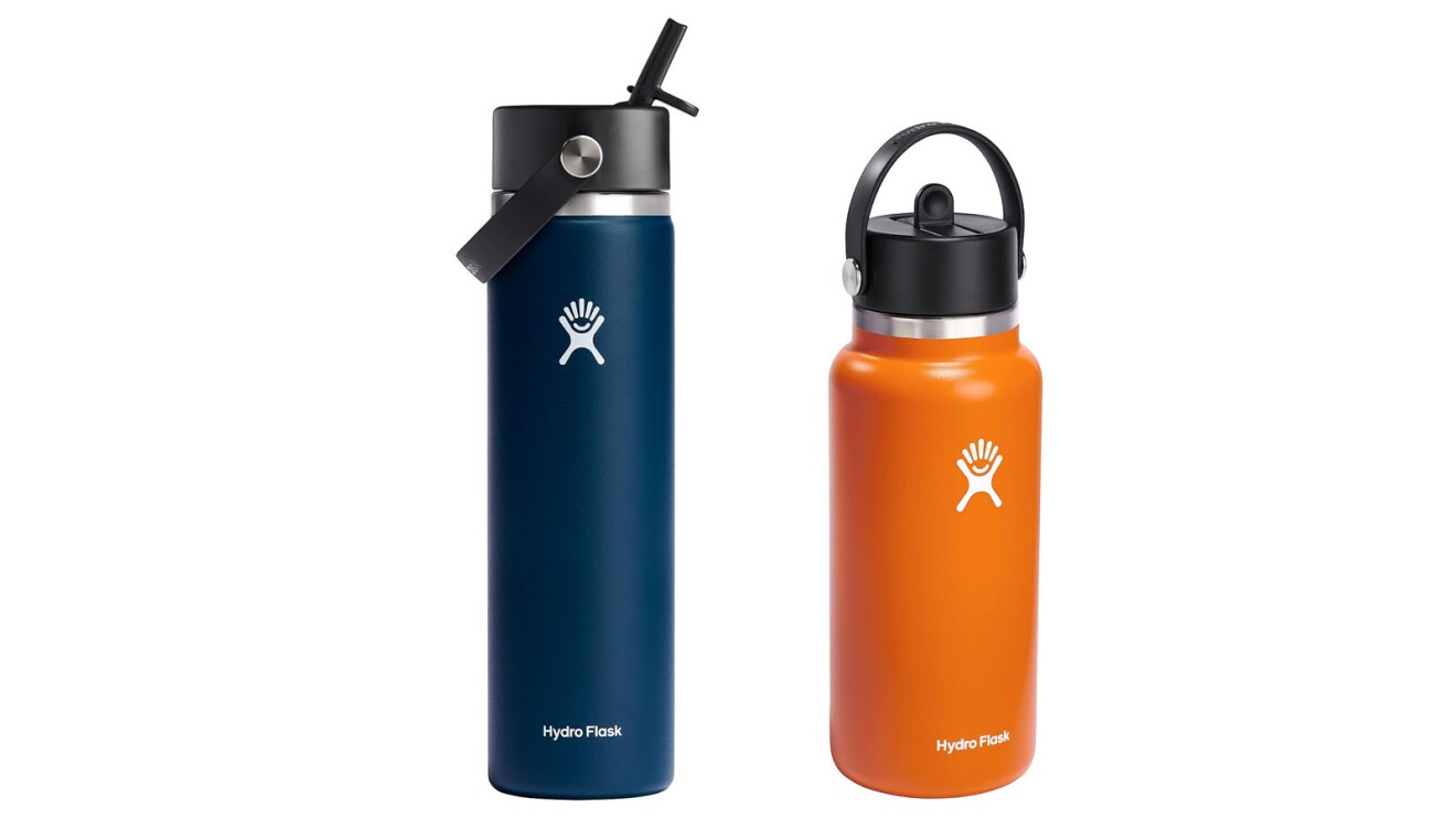 An image of two Hydro Flask water bottles. One is tall and thin with a straw in a dark blue color, and the other is shorter and wider with a screw on top and a handle on the lid in an orange color.