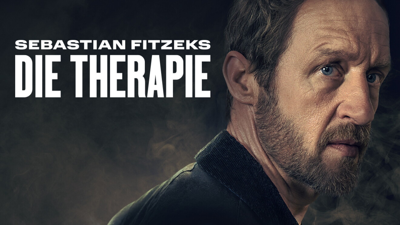 Aufmacher der neuen Prime Video Serie Die Therapie nach dem Buch von Sebastian Fitzek. Das Bild zeigt den Hauptdarsteller seitlich und den mysteriösen Umriss einer verglasten Haustür, hinter der der eine Frau erkennbar ist.