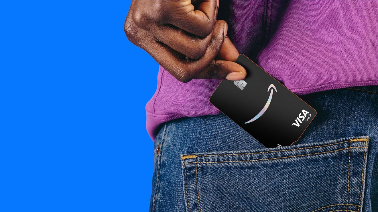Hand placing Amazon Visa card into denim pocket