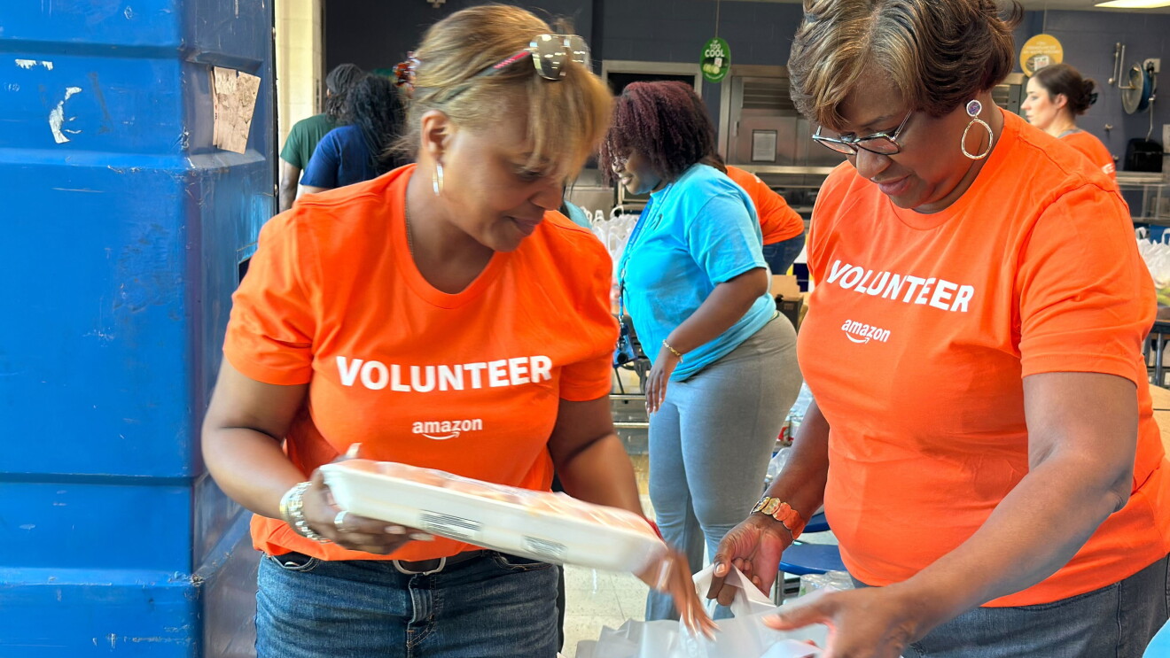 Amazon volunteers in bright orange shirts preparing supplies in Atlanta