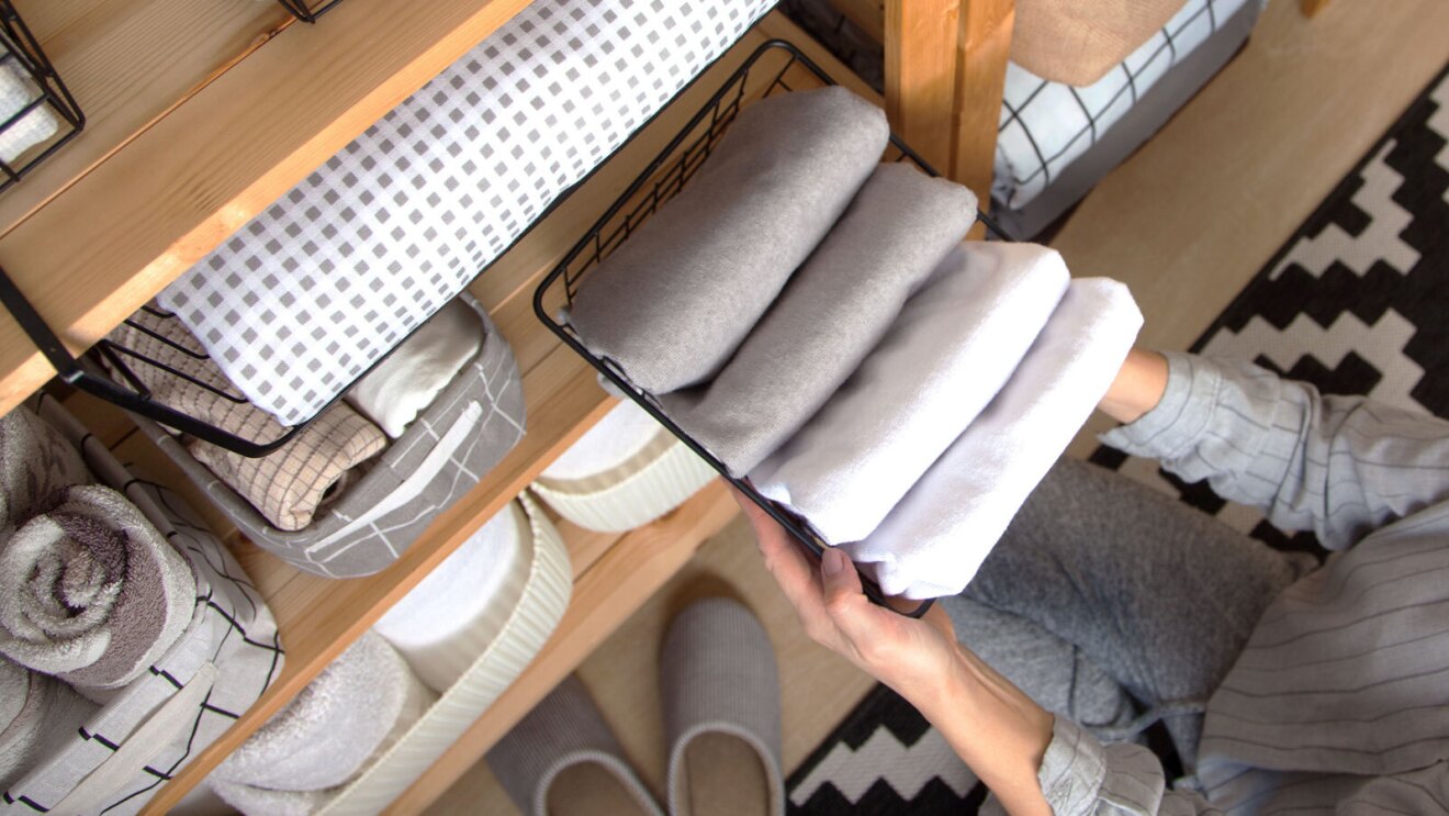 一个人把一个晒满了折叠床单在架子上。