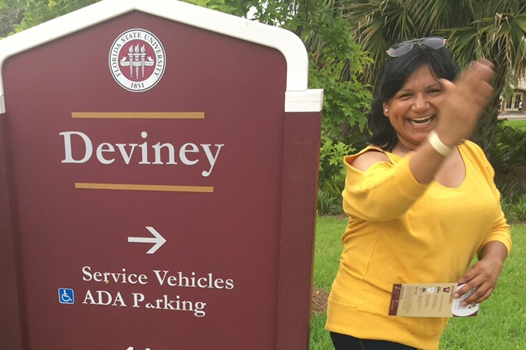 A smiling woman stands next to a Florida State University sign.
