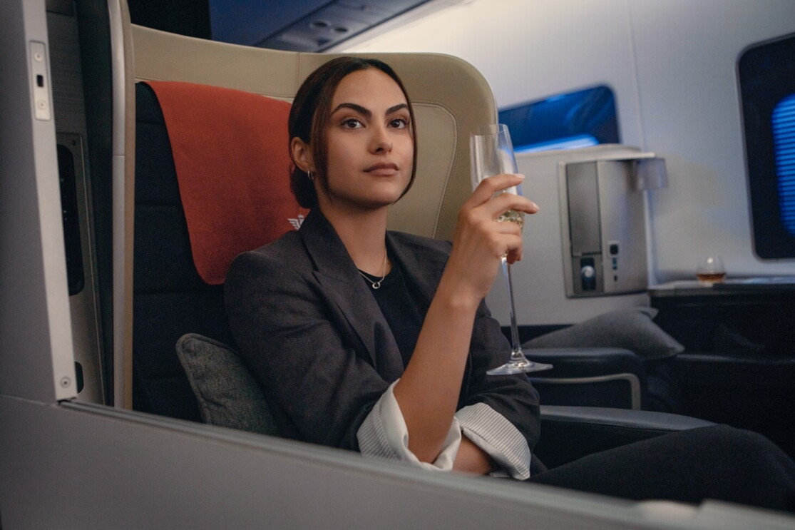 A young girl holding a glass of wine in an airplane