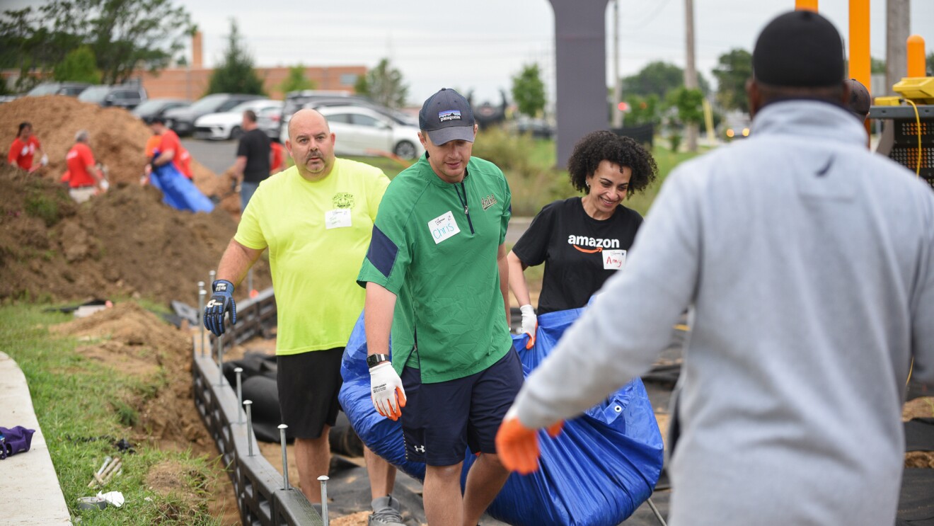 Amazon Volunteers in colorful shirts carrying supplies at community service event