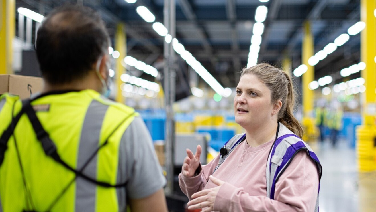Elizabeth talks to an employee at an Amazon fulfillment center.