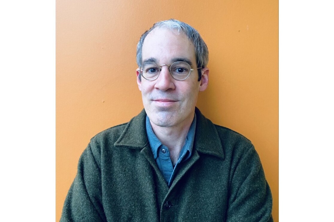 A headshot of Robb Kunz against an orange wall.