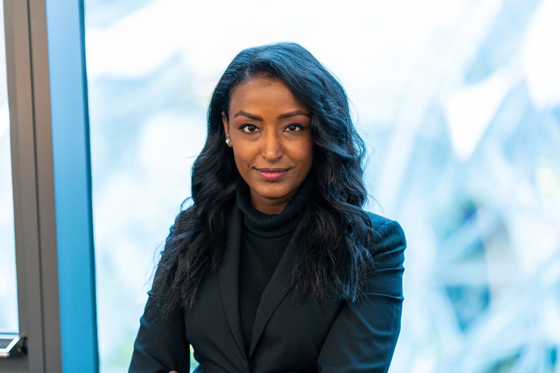 An image of a woman smiling for a headshot photo in front of a window. You can see part of Amazon's Spheres outside the window.