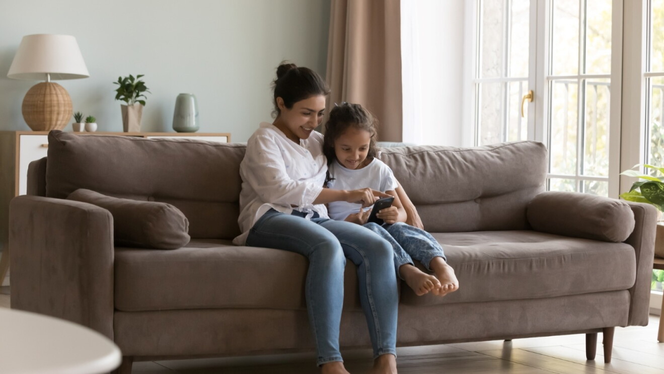 Woman and child sitting on couch looking at smartphone together