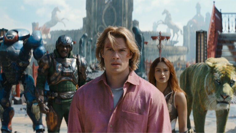 Nicholas Galitzine as He-Man with an ensemble of characters in the background.