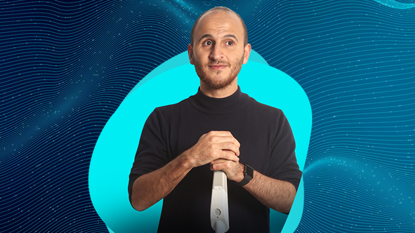 Kürşat Ceylan, co-founder of WeWALK holds a smart handle and wears a black shirt. He stands in front of  a blue graphic.