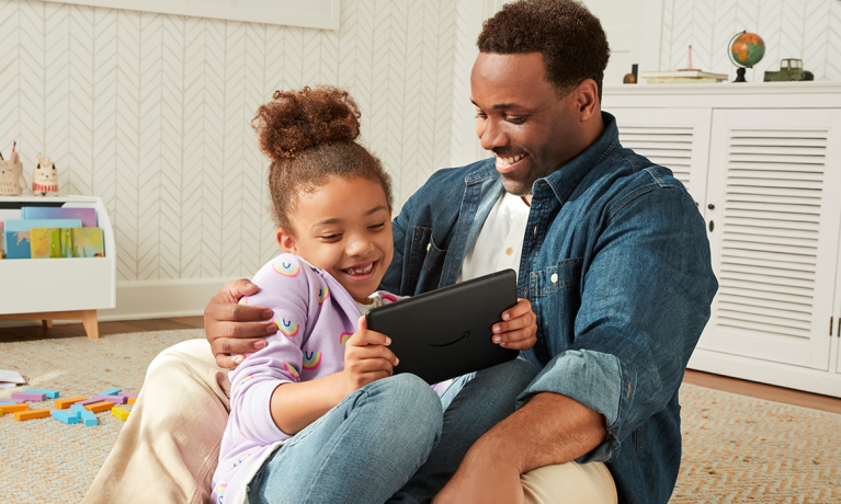 Young girl with her father playing with her kindle and smiling