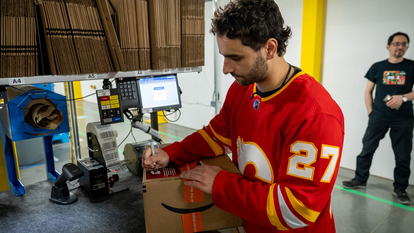 Two Calgary Flames hockey players packing and shipping Amazon boxes