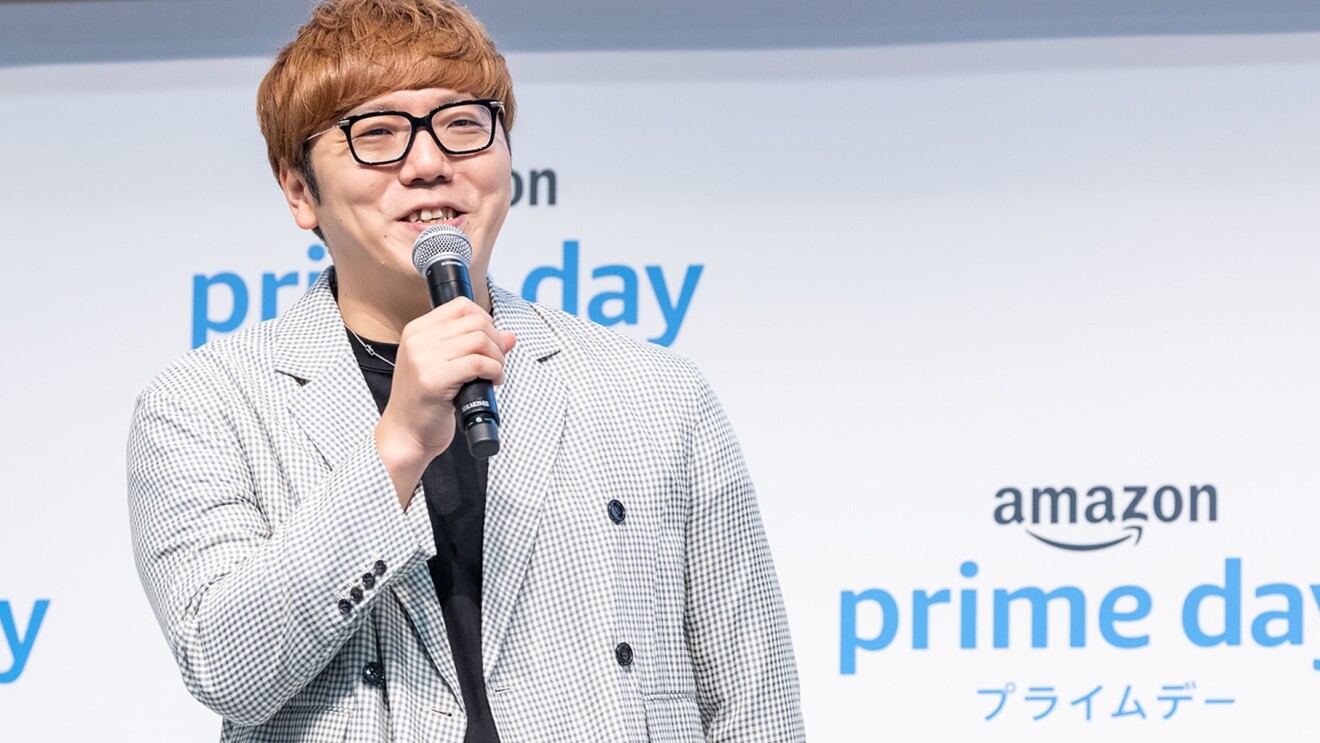 amazonプライムデーの文字を背景に笑顔で話すHIKAKINさん