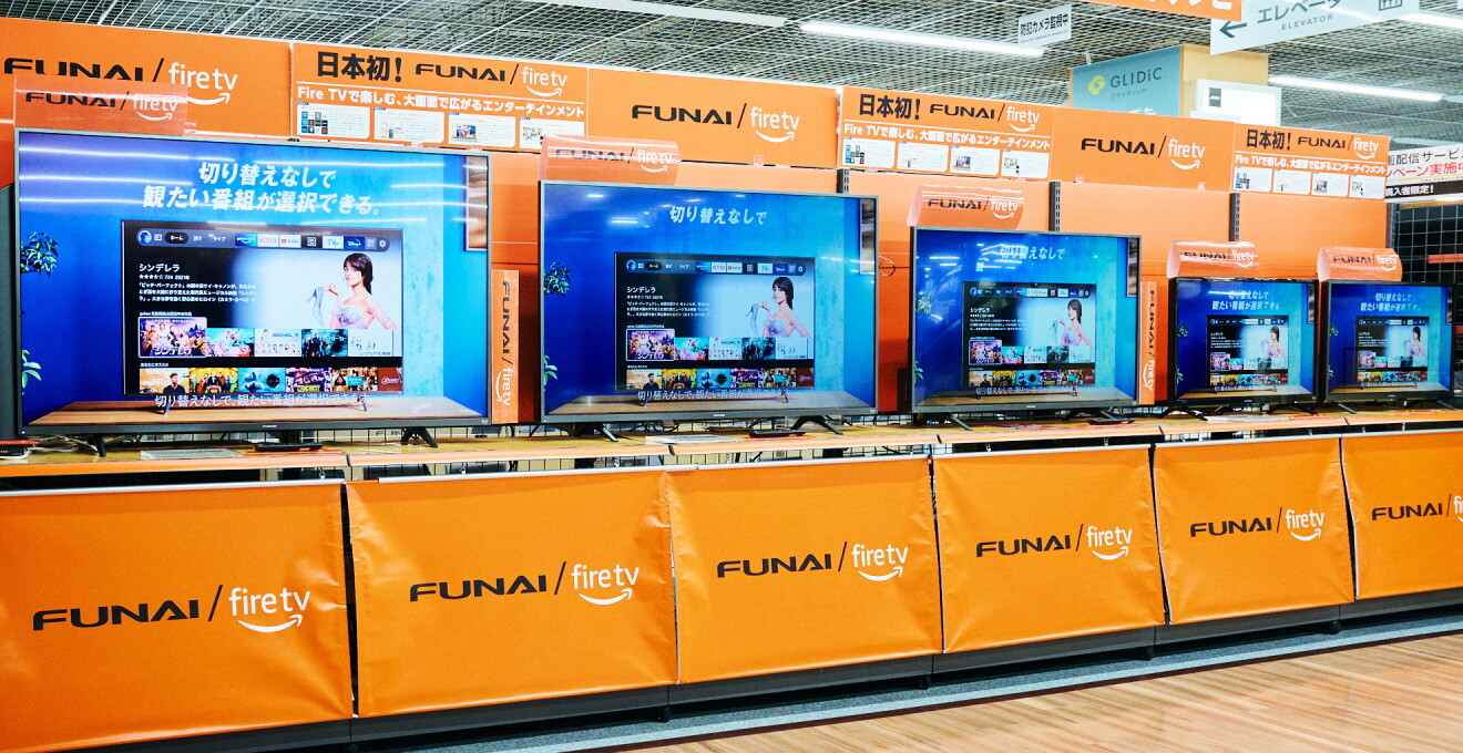 店舗内のオレンジ色の台に「FUNAI Fire TV搭載スマートテレビ」が５台並べられているそのうち４台はサイズが異なる