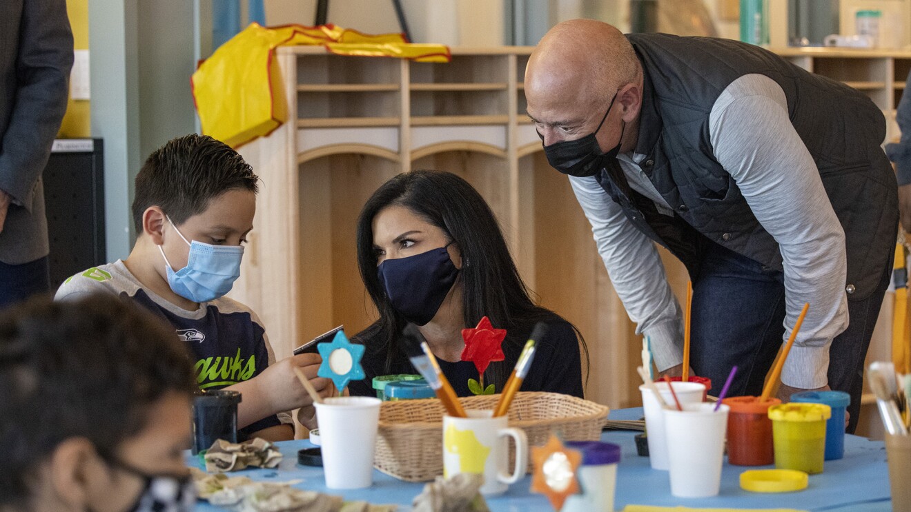 An image of Jeff Bezos and Lauren at an arts and crafts table with children staying at the Mary's Place Family Center.