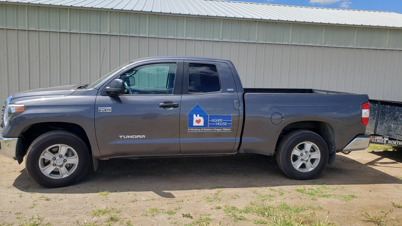 An image of a gray truck with a sticker on it that says "Agape House."