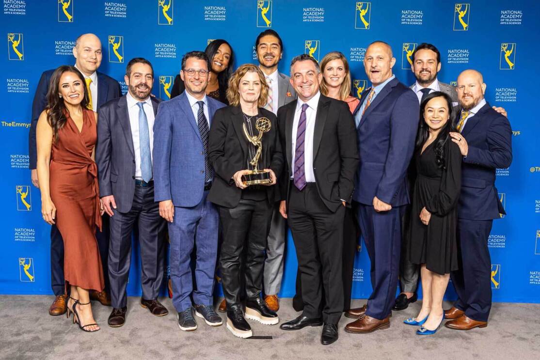 The Prime Video team posing to the camera and holding an Emmy award. 