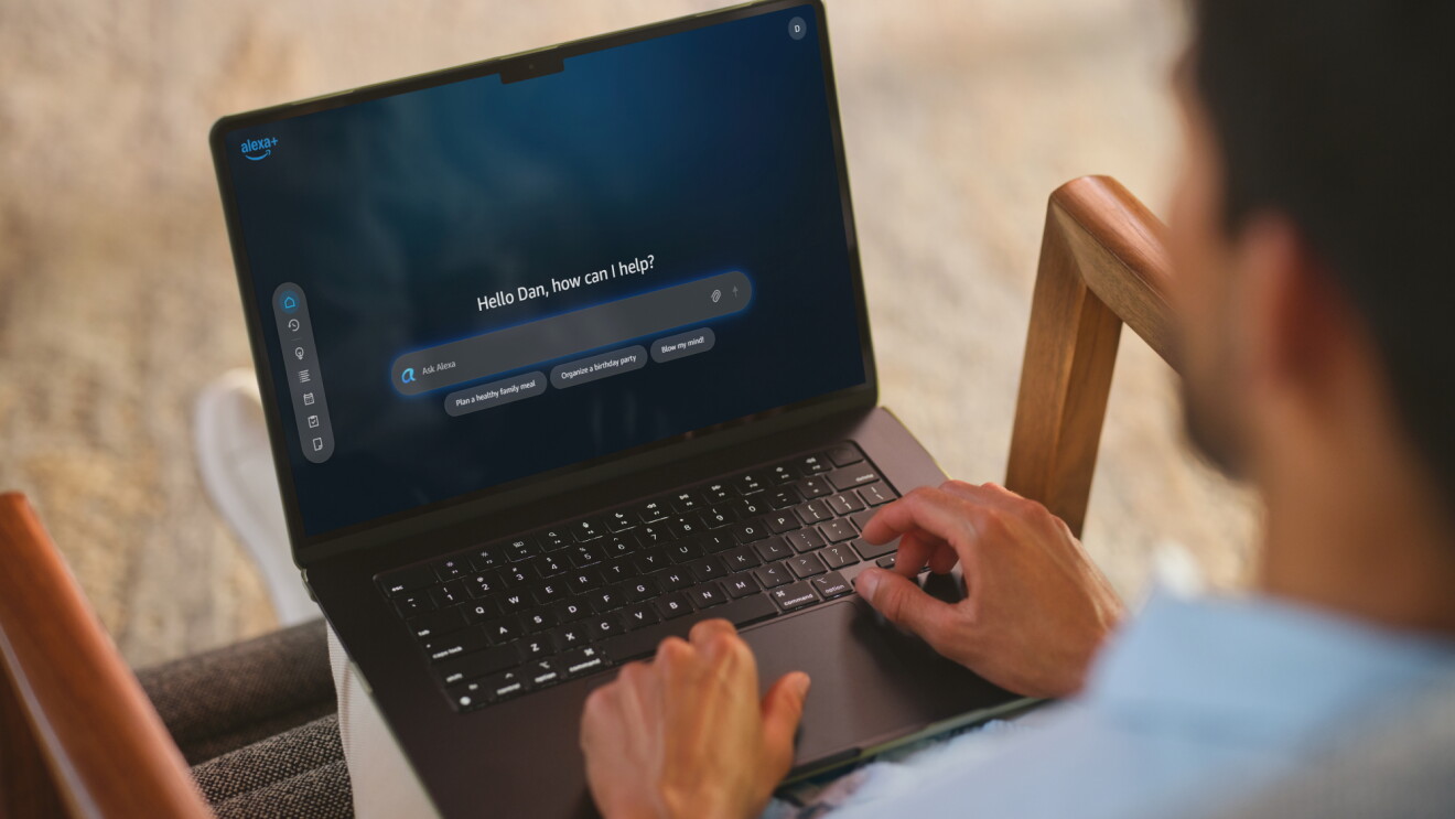 Person using laptop with Alexa+ assistant interface displaying 'Hello Dan, how can I help?'