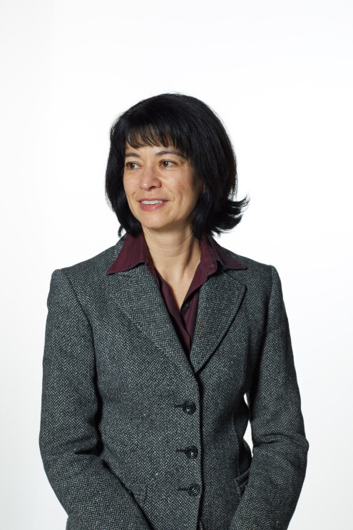 A headshot of Jacqui Chin wearing a greay blazer and looking to the left.