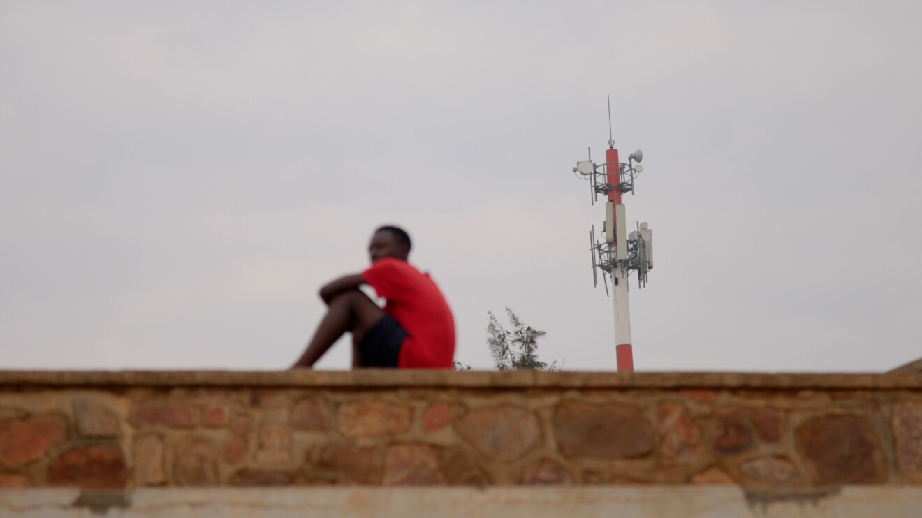 Person sitting on stone wall overlooking cellular tower