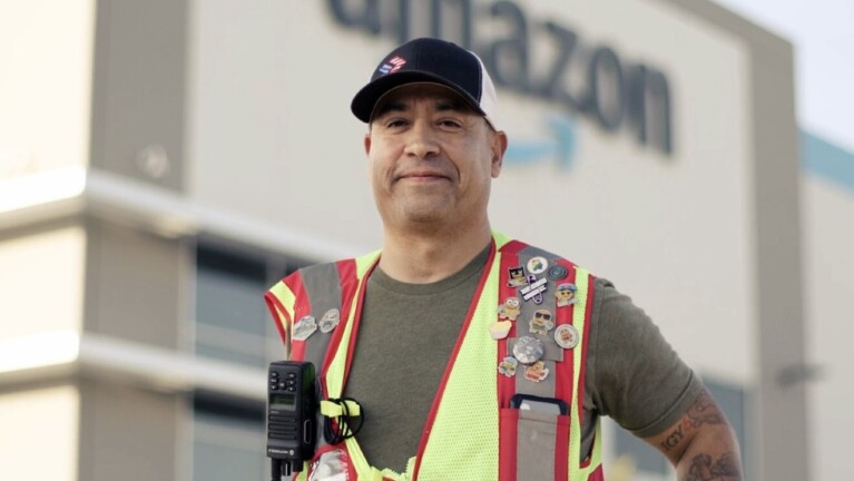 A photo of Norbie Lara, Assistant Site Leader, standing in front of a Fulfillment Center in Fresno, California.