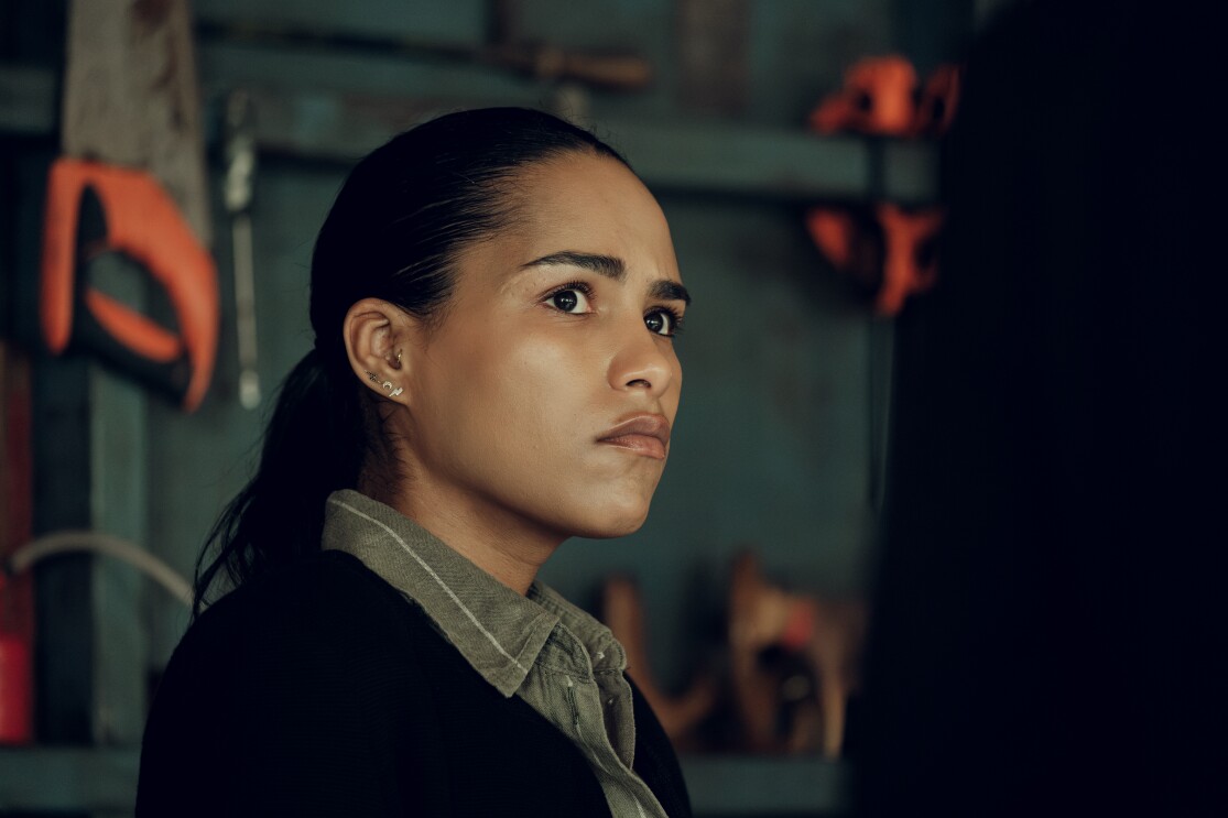 A young woman with black hair looks ahead angrily