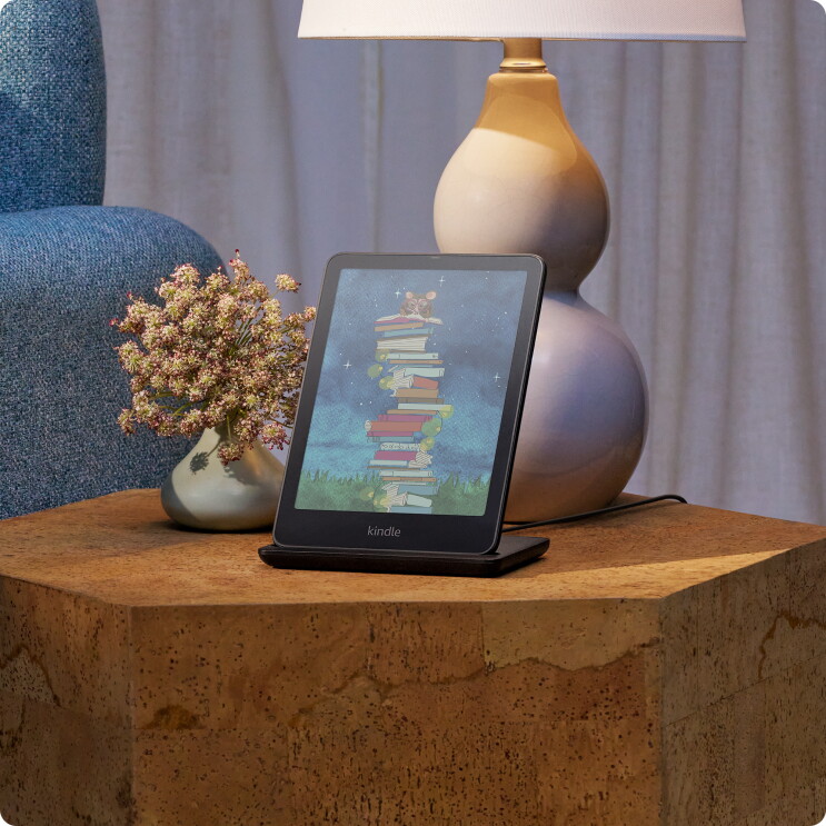 A Kindle Colorsoft on a table with a lamp and flower vase