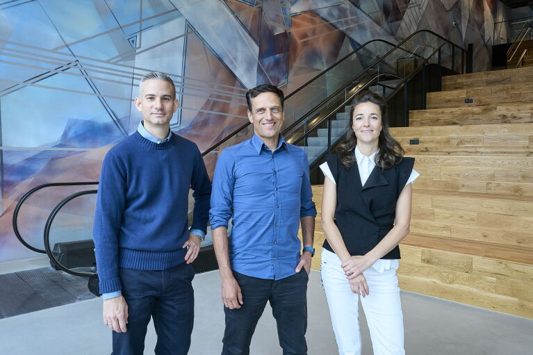 Jonathan Weiß, Leiter des Forschungs- und Entwicklungsstandorts von Amazon in Berlin, Rocco Bräuniger, Country Manager von Amazon in DACH, und die Künstlerin Alina Mann vor dem 180m2 großen Wandgemälde "Unfold" im EDGE East Side Berlin.