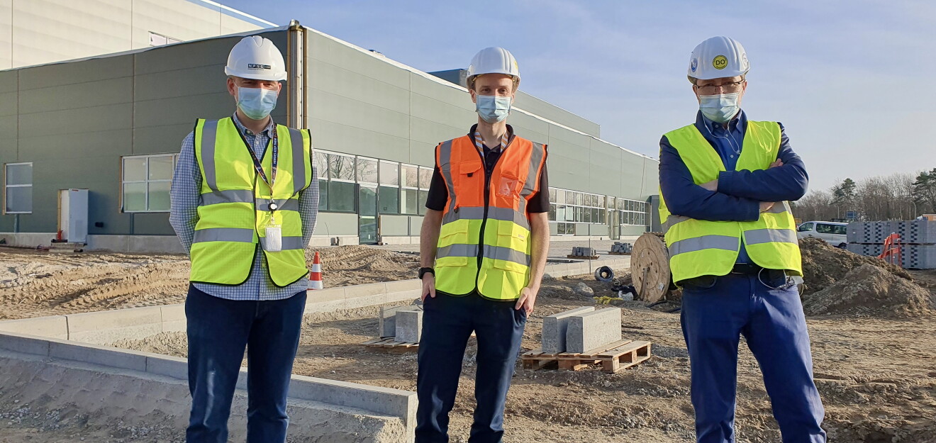 3 Männer in Helm, Sicherheitswesten und Masken vor dem neuen Amazon Logistikzentrum in Achim