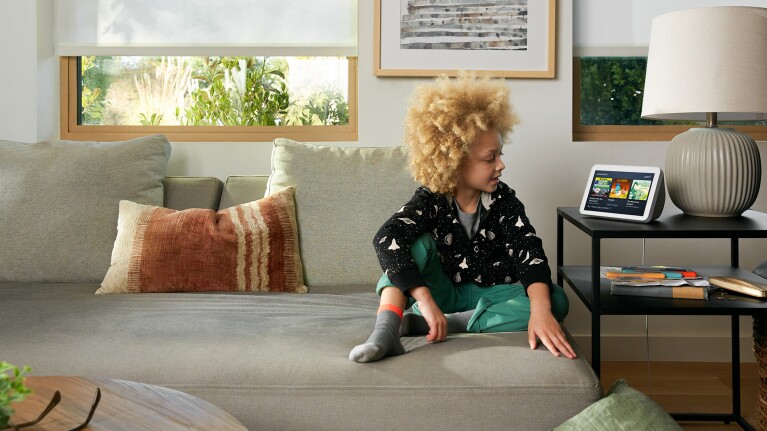 An image of a boy interacting with an Echo show in a living room. 