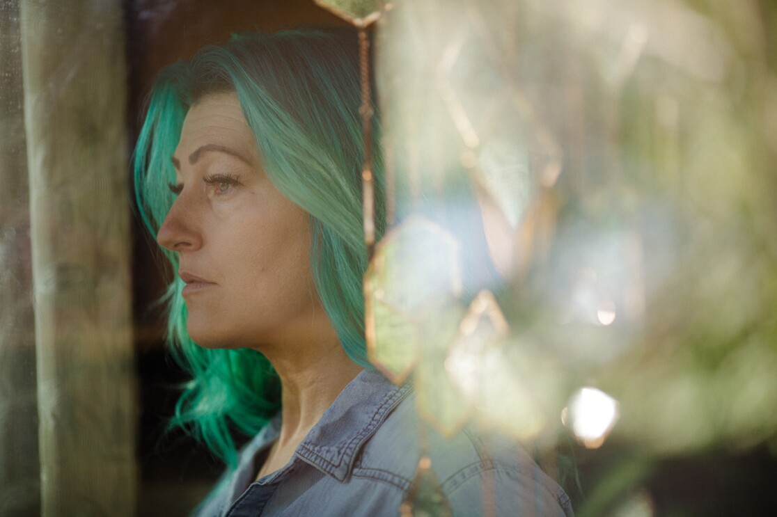 A woman with long green hair photographed in profile.