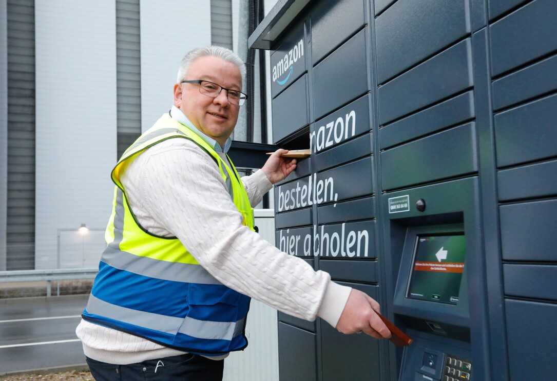 Ein Mann in Sicherheitsweste vor einem Amazon Locker