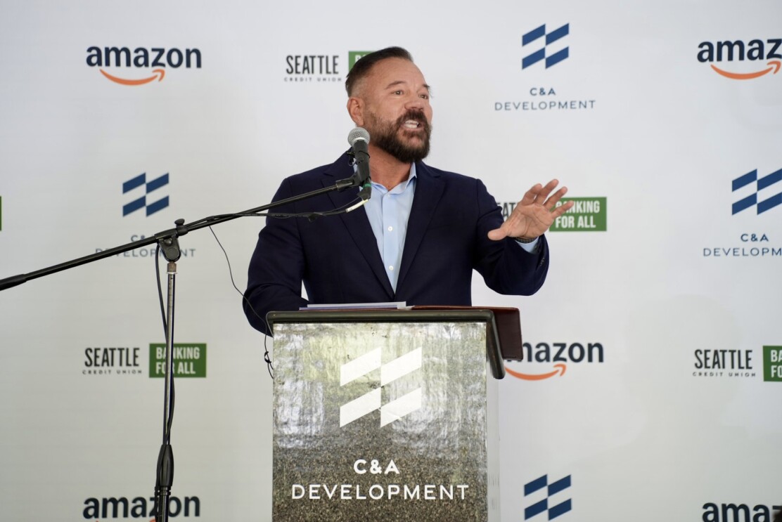 Amazon VP of Public Policy Community Engagement Brian Huseman stands behind a podium speaking to an audience of community advocates and business leaders