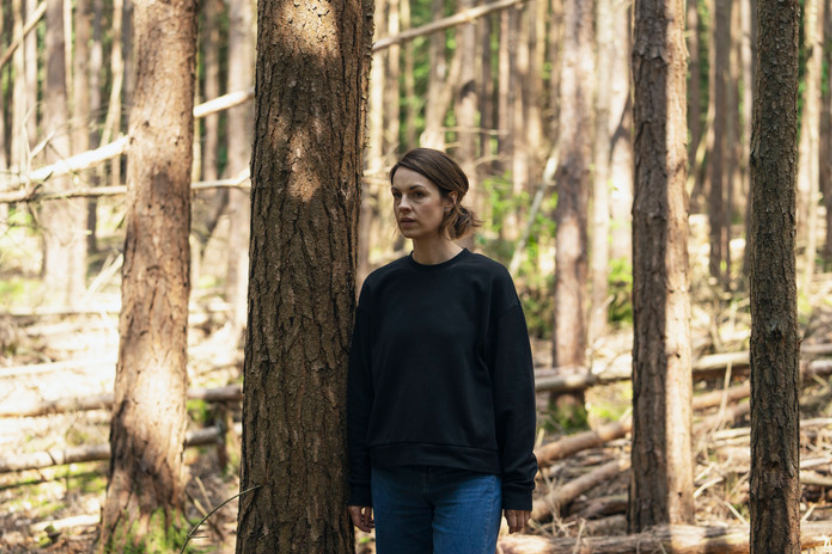A brunette woman stands in the forest