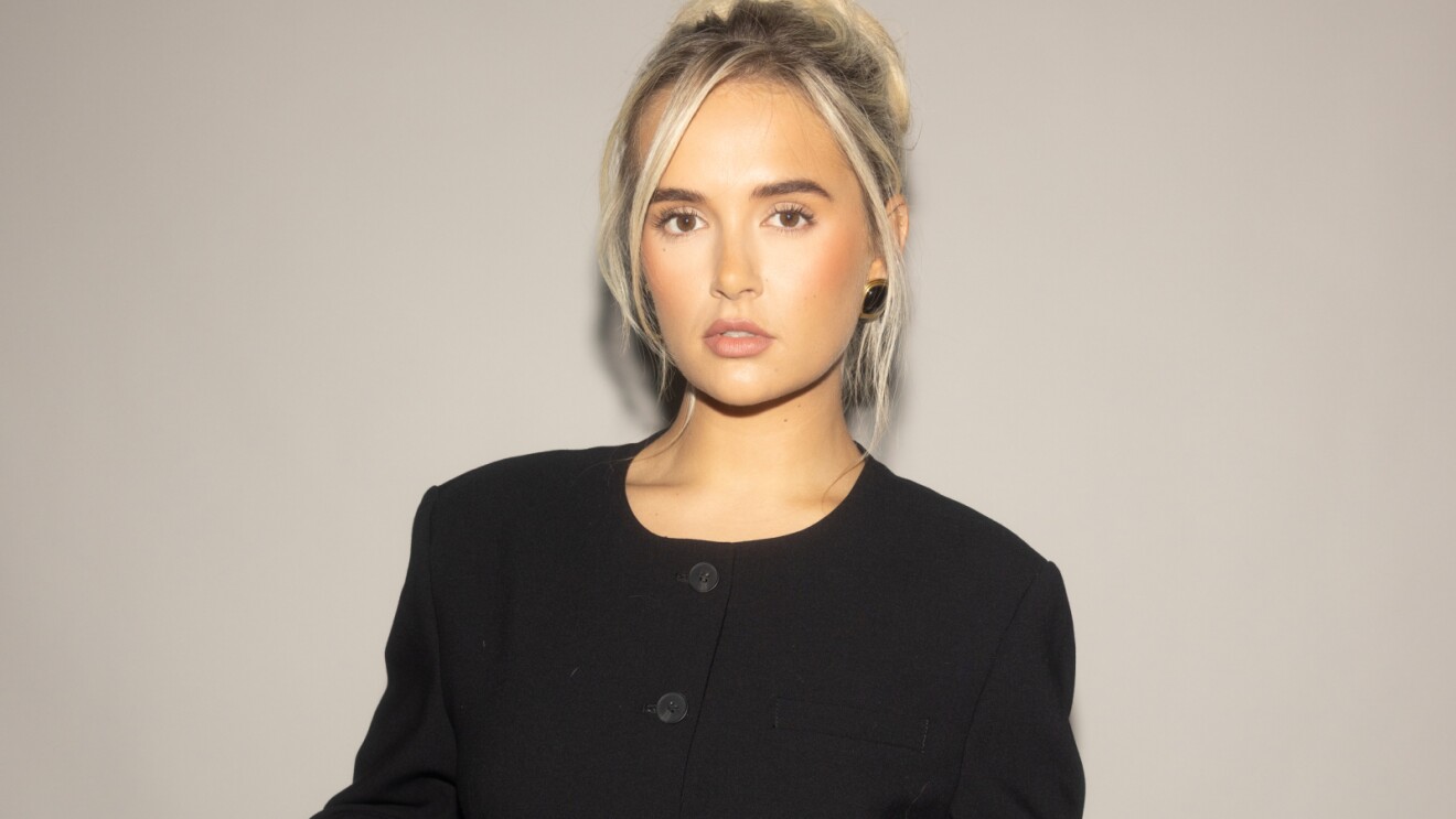 Young blonde woman in black top gazing intently at camera