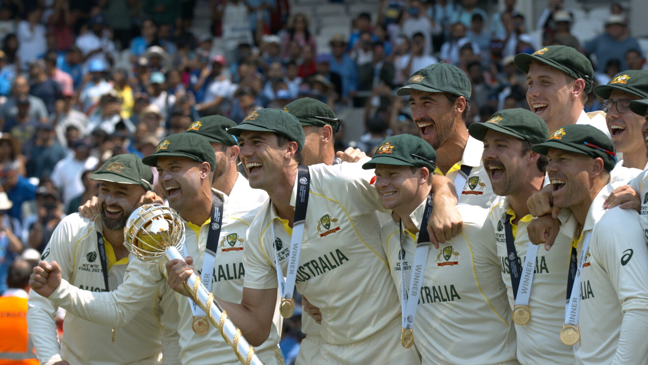 Australian men's cricket players smiling and holding a trophy 
