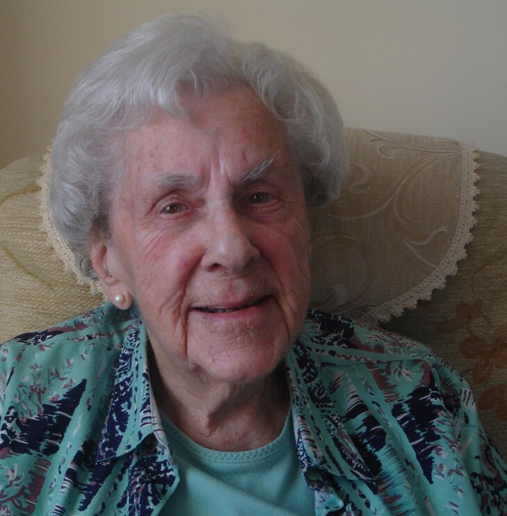 lady with grey hair wearing a blue top and looking straight at the camera