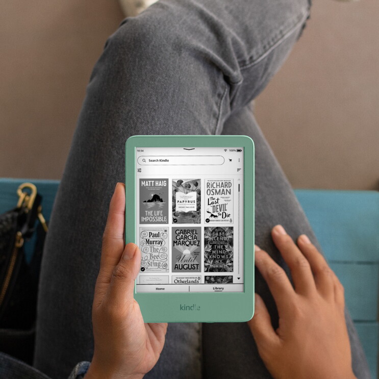 Someone sat down holding a Kindle in the new Matcha colour