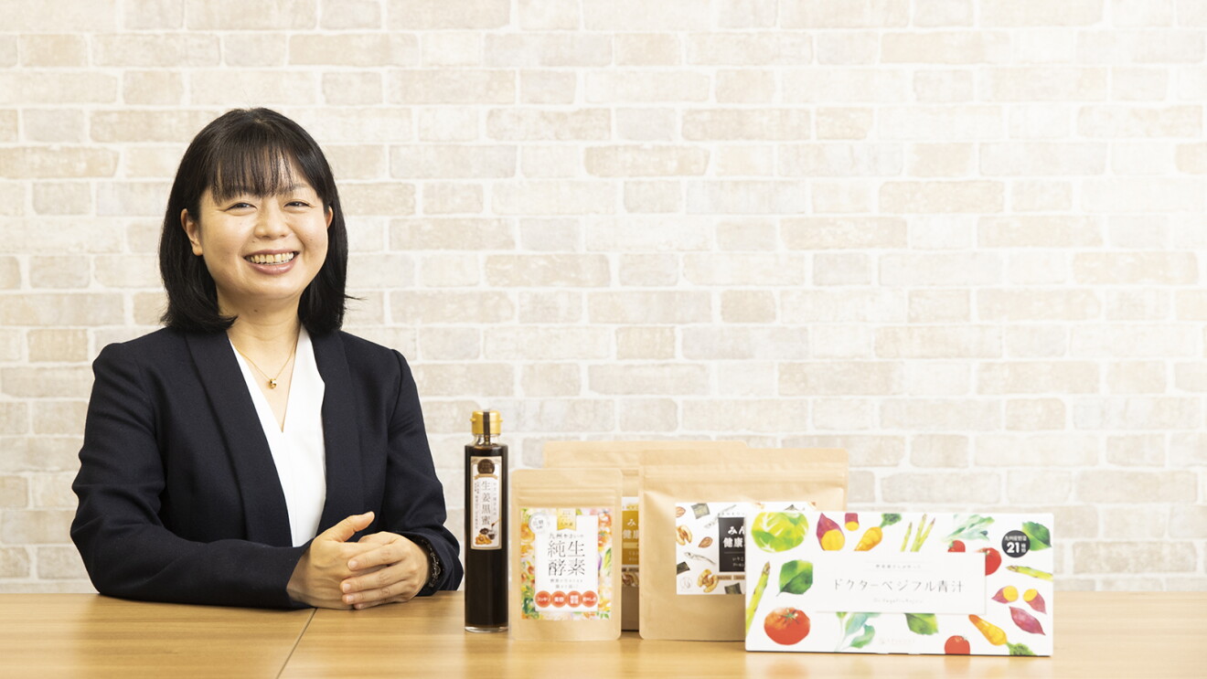 商品と並んで笑顔の植木さんの写真