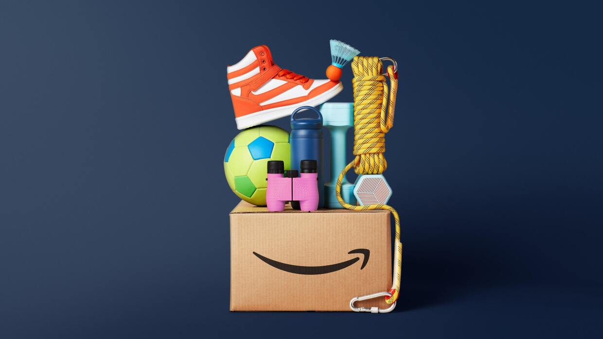 Cartel de la campaña: 15 cosas que no sabías sobre Amazon. Encima de una caja de Amazon hay productos relacionados con el deporte. 