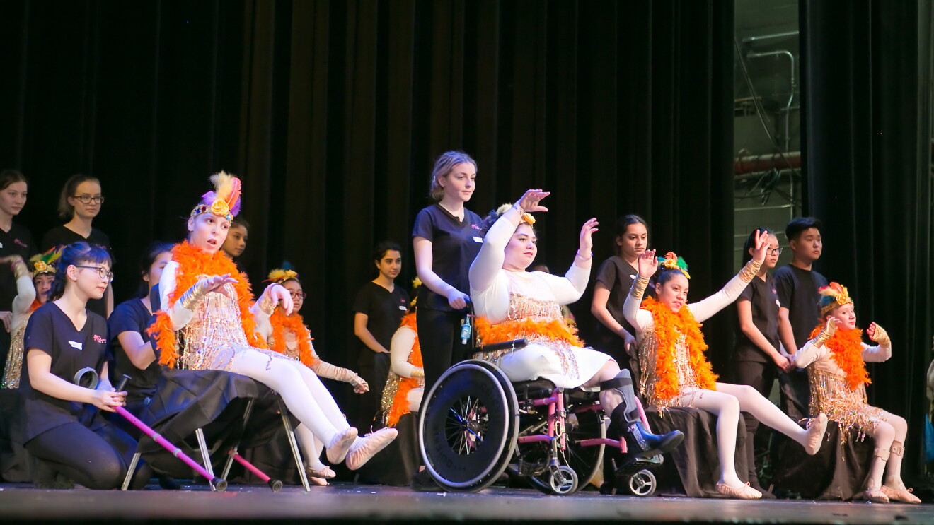 Students at Dancing Dreams, performing on stage in their recital. Many of the students have aides to support them. 