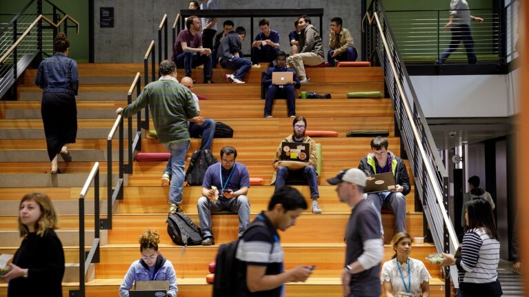 Multilevel seating area filled with Amazon employees using laptops and phones