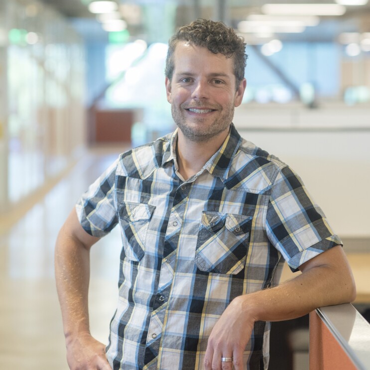 A man wearing a plaid shirt, smiling at the camera.