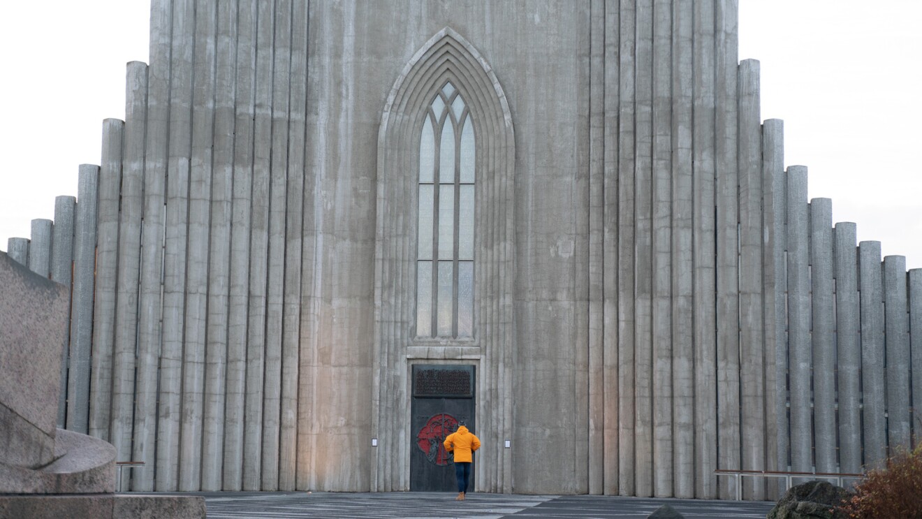 一个穿着黄色外套的人站在灰色高墙上的两扇门前。